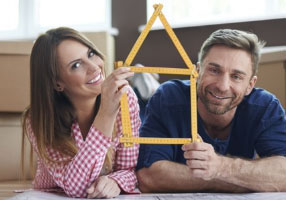 casal feliz segurando um enfeite em formato de casa